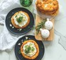 Two plates of lángos topped with soured cream and cheese next to a stack of them