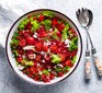 Bowl of salad topped with pomegranate and tomatoes