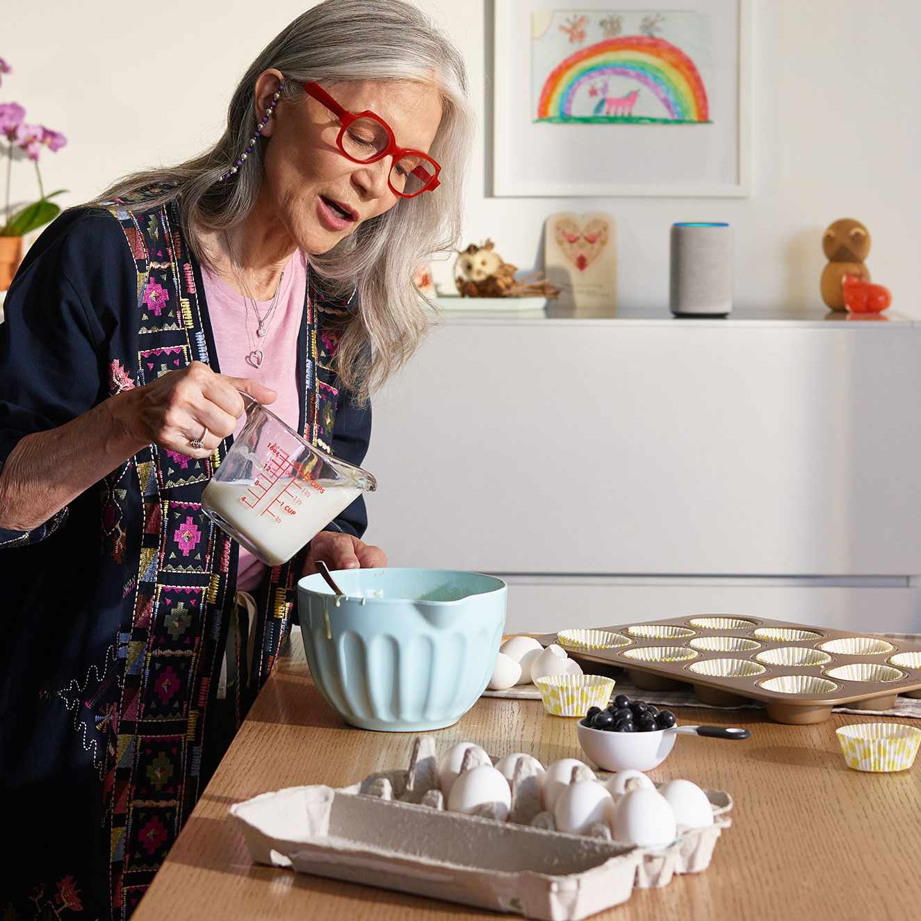 Woman in a kitchen cooking with an Amazon Echo device in the backgound