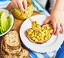 Coronation chickpea sandwich filler being spread onto a slice of bread