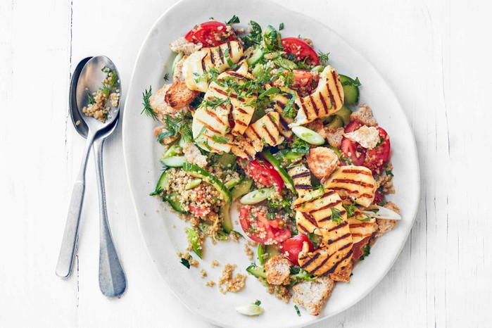 Halloumi & quinoa fattoush on a white serving plate next to two silver spoons