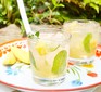 Mango and pineapple cocktail with mint on tray with lime wedges