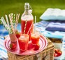 Strawberry lemonade served in a bottle and two glasses with straws