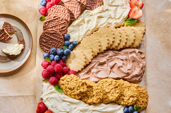 Summer fruits, biscuits and cheesecake mix arranged in swirls on a serving board